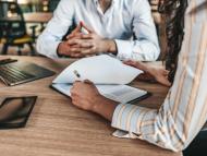 Gros plan d'une main féminine signant un document formel sur la table d'un bureau